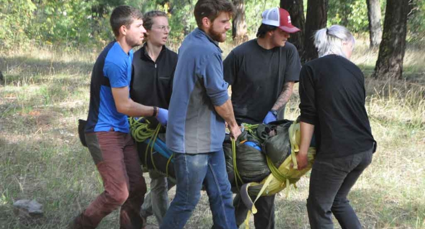 five people carry someone during a wilderness first responder course